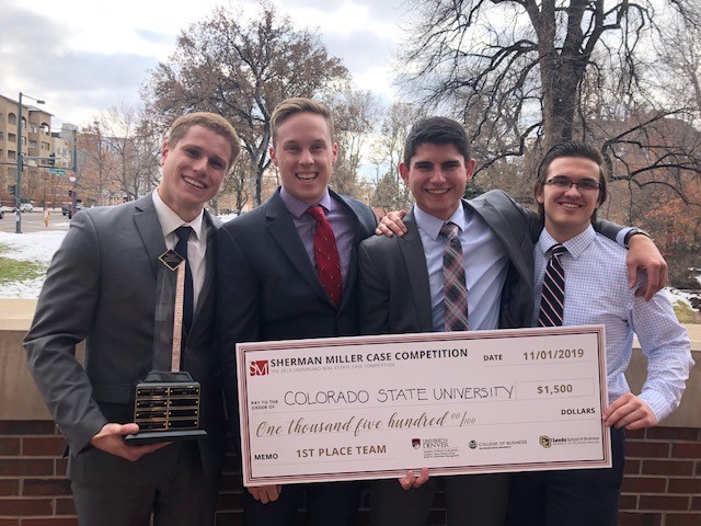 Real estate students stand with check after winning competition