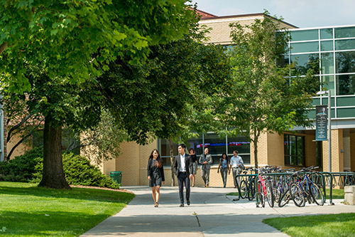 Two students walk past the front of the Rockwell West building
