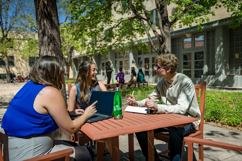 Students chat at a table outside the Lory Student Center