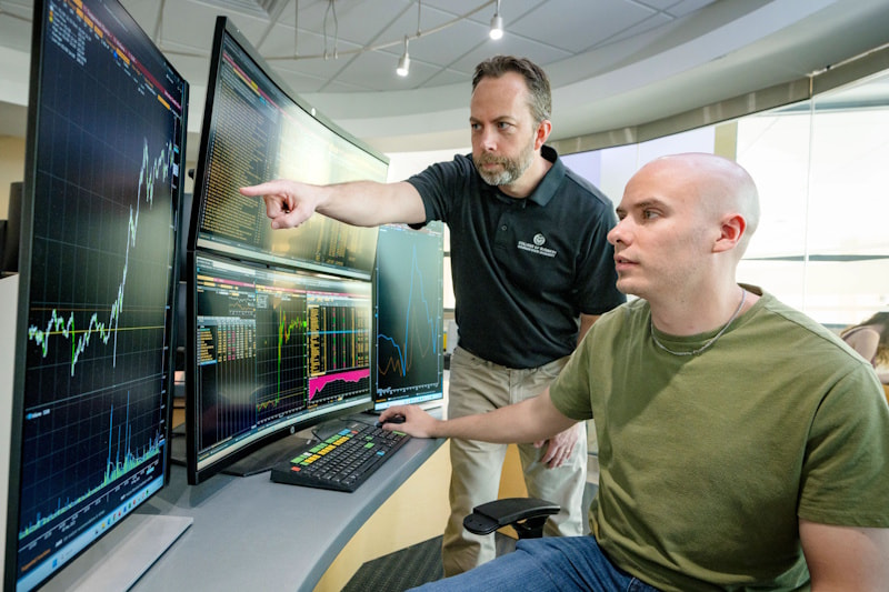 A student and a faculty member discuss something at a Bloomberg terminal.