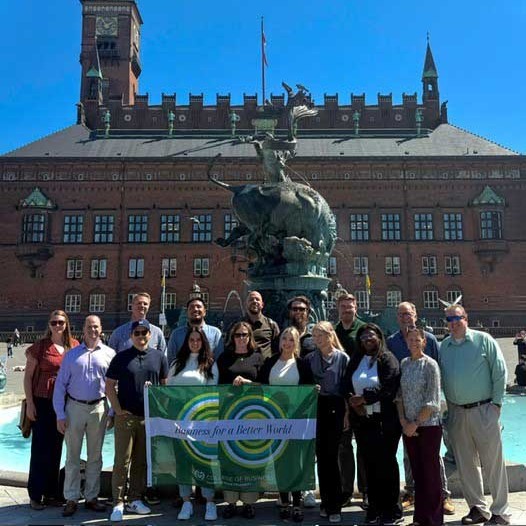 CSU MBA students and faculty pose for a photo in front of an old municipal building in Copenhagen.