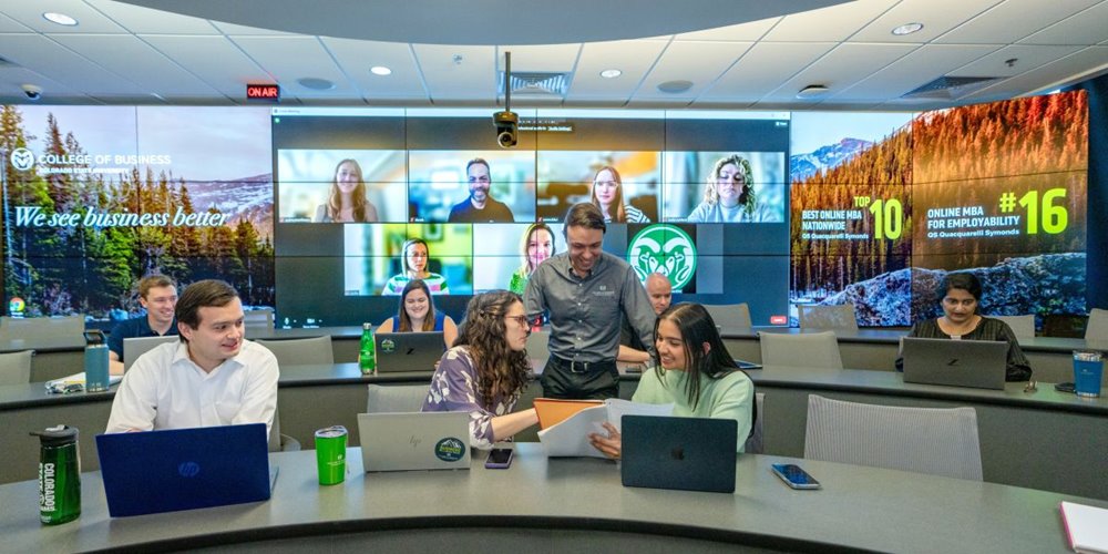 Professor Paulo Borges de Brito, PhD. talks with a pair of students in an Evening MBA class as Mosaic MBA students engage in the discussion remotely.