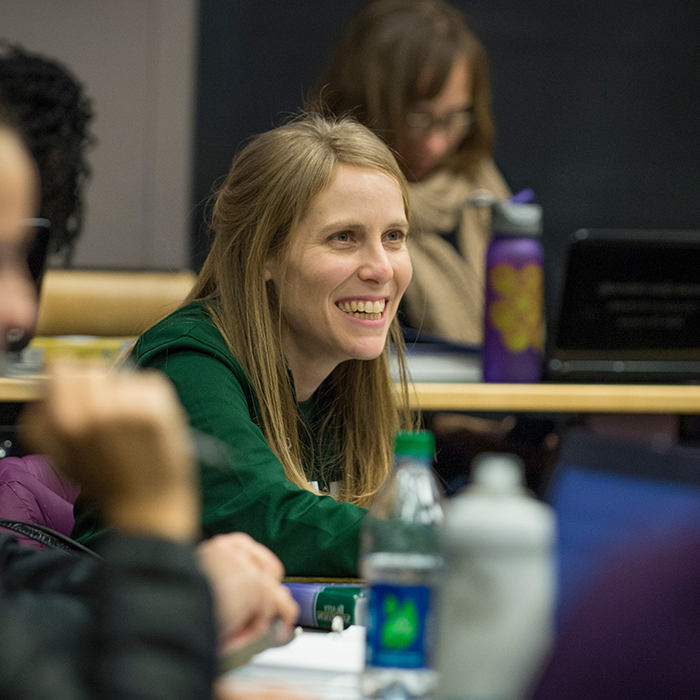 An MBA student smiles while listening to a lecture