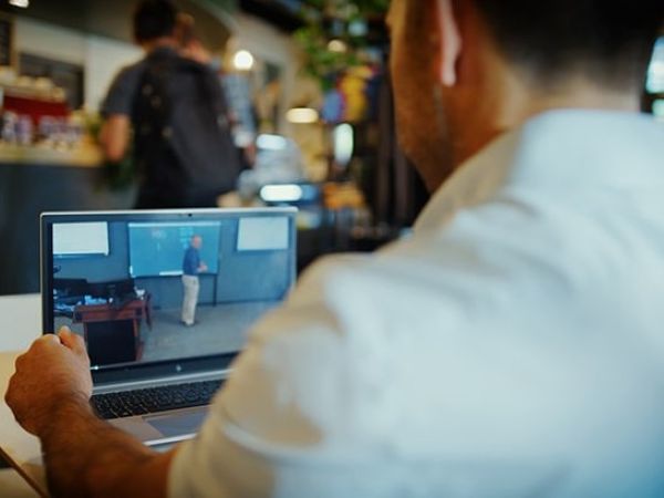 A student watches an Online MBA lecture from his laptop in a cafe.