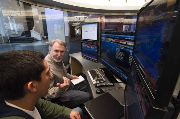 A student and a faculty member discuss something at a Bloomberg terminal.