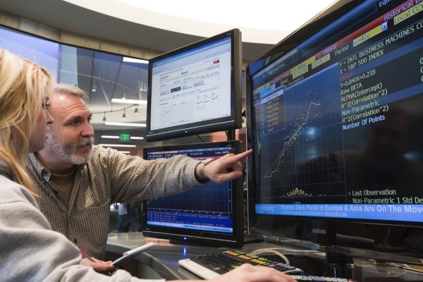 A student and a faculty member discuss something at a Bloomberg terminal.