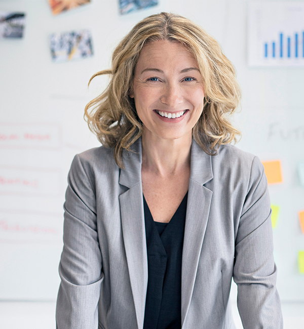 A smiling woman stands in front of a white board