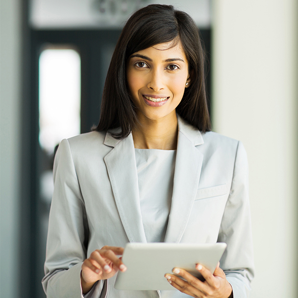 A business woman smiles while holding onto a tablet