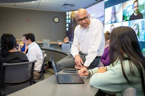 A CIS professor listens to a student discuss an assignment in the Mosaic classrtoom.