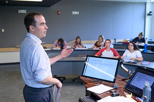 A business professor stands at the front of a classroom