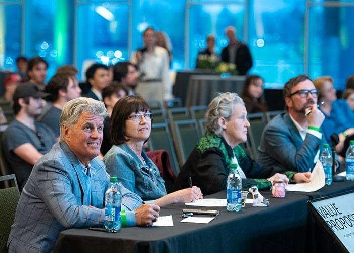 A panel of judges watch a case competition presentation.