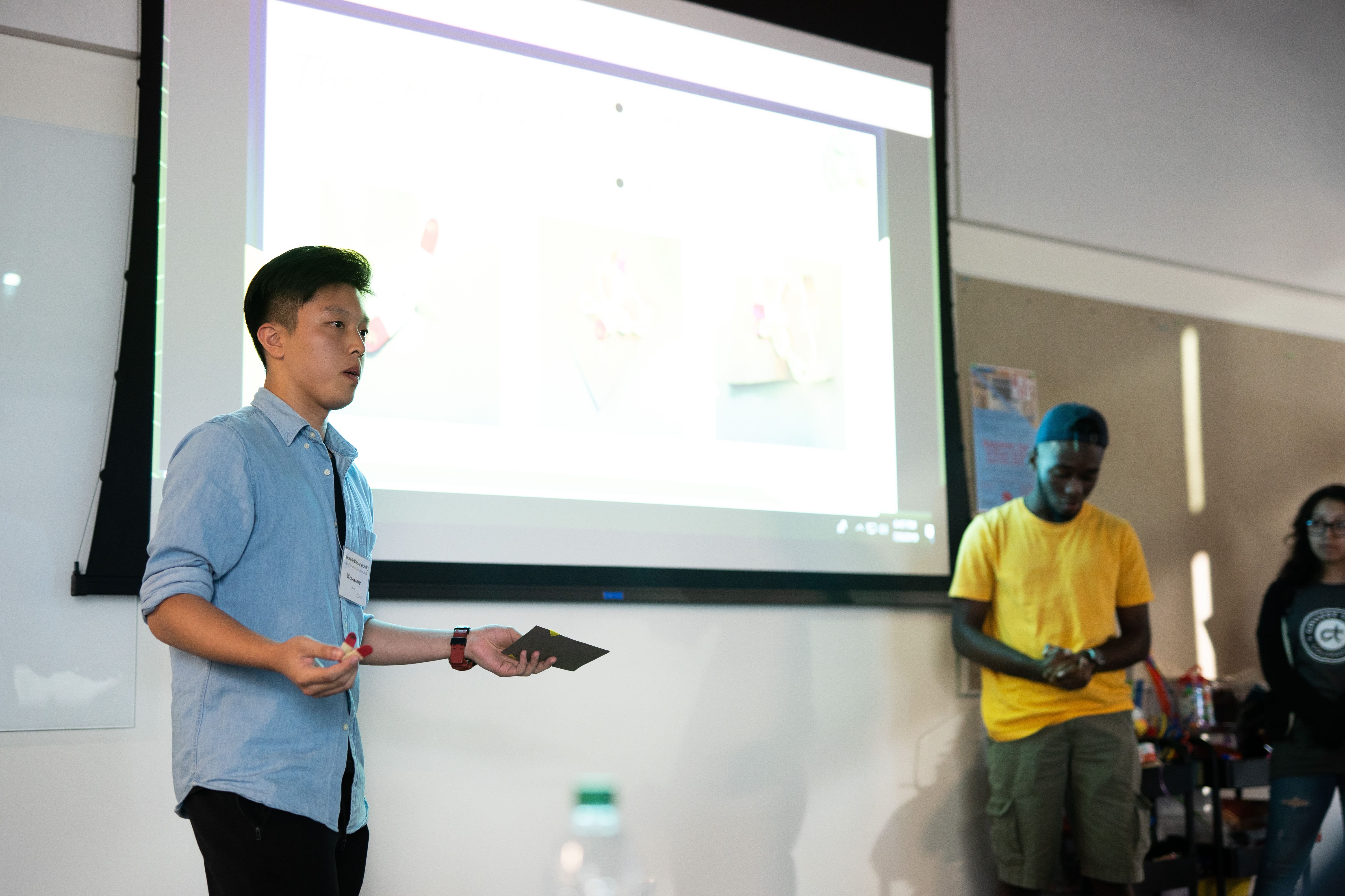 Two student stand in front of a classroom and give a presentation