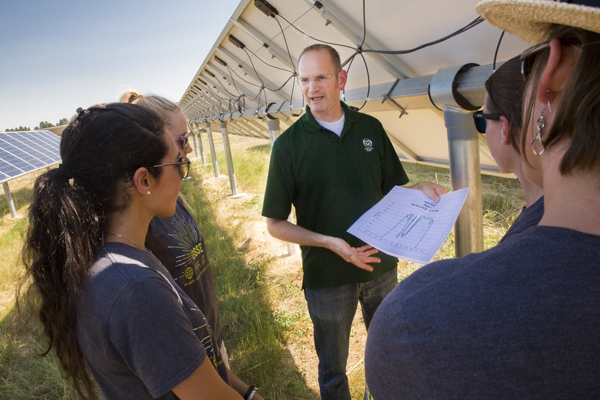 Campus Energy Coordinator Stacey Baumgarn works with Impact MBA students at a solar farm.