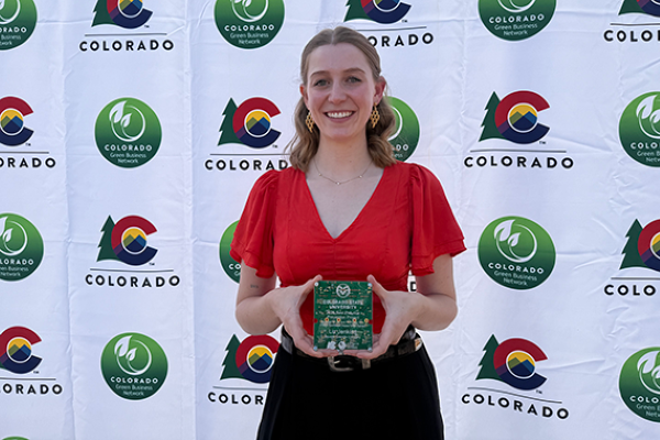 Liz Jenkins posing for a picture with the Best Pollution Prevention Project Award she received from the Colorado Green Business Network.