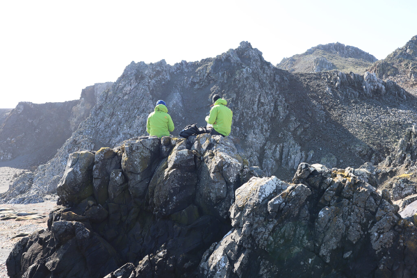Researchers sit on some rocks overlooking a vista in the Arctic.