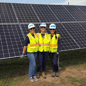 Impact MBA studenst pose for a photo in front of solar panels.