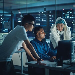 Three cybersecurity students work at a computer