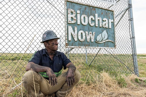 Mike Rowe sits in front of a Biochar sign