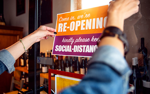 An open sign with a message about social distancing