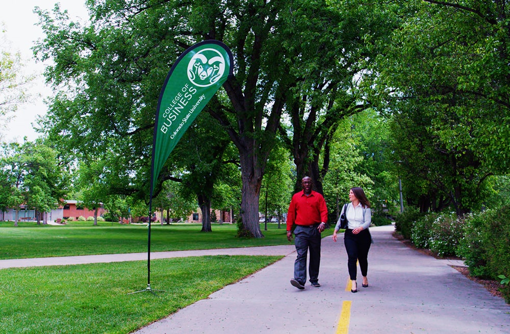 Two MBA Students walk past a College of Business banner