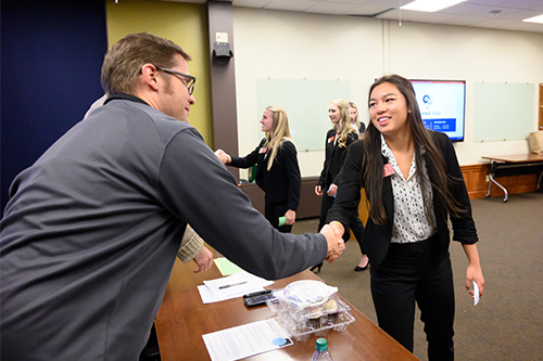 A student shakes hands with a judge during a case competition