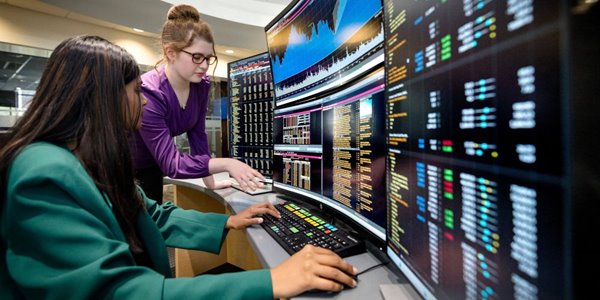 Two finance studnets work at the College of Business's Bloomberg terminal.