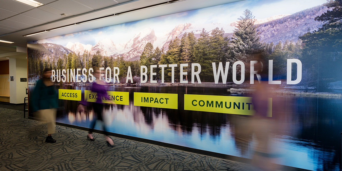 College of Business students walk past a wall sign that reads 