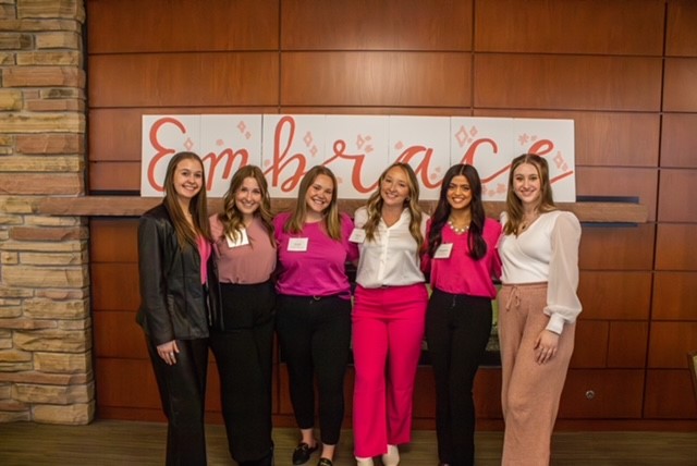 Women in Business Association student leadership pose for a photo. at a tabling event.